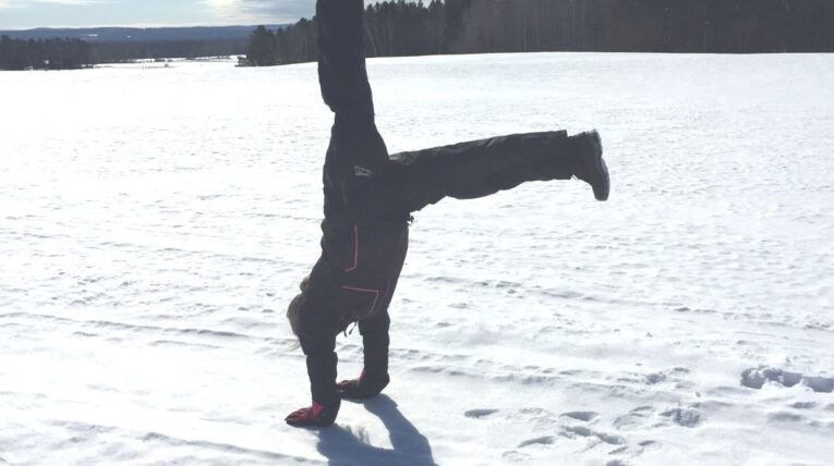 girl doing handstand in snow